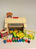 Overall view of School House building, vehicle, swing, slide, merry-go-round, eight Little People figures and animal figure