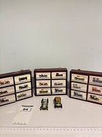 Three wood display cases with boxed miniature cars and two loose cars in front