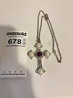 Front view of Sarah Coventry cross pendant necklace showing faux pearls and purple center stone