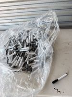 Full view of open clear bag filled with white barrel black-cap dry erase markers on table