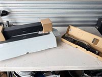 Soundbar on top of original box with accessory tray beside it