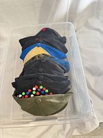 Stack of seven caps in plastic bin