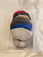 Stack of seven caps in plastic bin