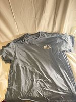 Stack of grey Gildan DryBlend T-shirts showing front and logo