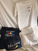 Stacked black and white graphic T-shirts displayed on sheet