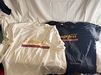 Stack of white and black Cottagefest T-shirts showing front graphic