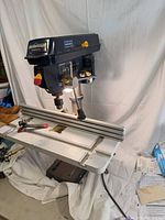 Full view of Mastercraft bench drill press on table with aluminum fence and clamp