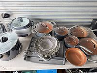 Overview showing rice cooker, slow cooker, stack of pans, strainers, baking trays