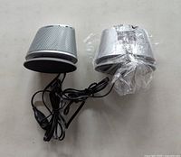 Pair of silver Amazon Basics speakers showing overall condition and attached cables