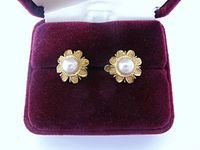 Front view of both gold flower earrings with pearl centres in box