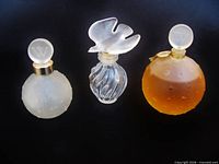 Front view of three perfume bottles displaying shapes, stoppers, and color differences