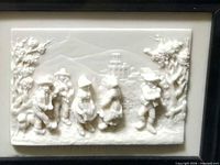 Close-up of white limestone bas-relief plaque showing detailed figures and landscape