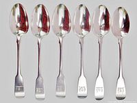 Front view of six sterling silver teaspoons showing engraved crests