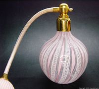 Close view of bottle showing pink and white latticino ribbons and gold hardware
