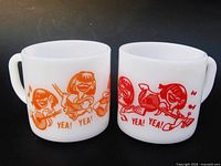 Front view of both milk glass mugs showing orange and red Beatles graphics