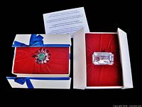 Both boxed figurines side by side with lids open showing contents and information card