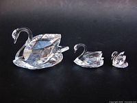 Three crystal swans side by side showing graduated sizes