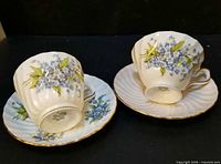 Both Aynsley cup and saucer sets viewed from side angle