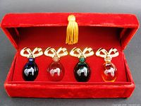 Front view of four colored miniature perfume bottles inside red velvet box