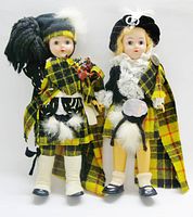 Front view of both Scottish piper dolls showing attire and accessories