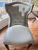 Front view of one chair showing tufted backrest, nailhead trim, upholstery