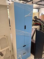Front view of tall blue and white storage cabinet showing two doors and two drawers