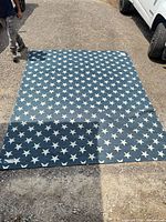 Full view of blue rug with white stars laid out on gravel