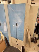Front view of one blue and white wardrobe cabinet wrapped in plastic film