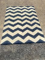 Full view of navy and white chevron rug on ground