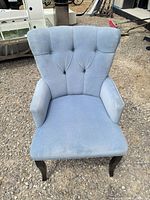Front view of light blue tufted armchair showing fabric, tufting and leg style