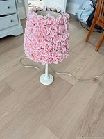 Full view of lamp showing pink rose-covered shade, white base and power cord