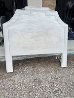 Front view of ivory upholstered queen headboard with nailhead trim and attached legs