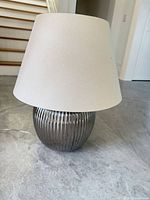 Full view of lamp with shade showing gunmetal base and beige shade