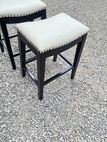 Two stools angled to show seat upholstery, nailhead detail, frame colour