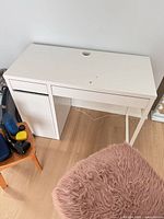 Front and top view of assembled white desk showing overall design, drawer, cabinet and cable grommet