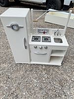 Full view of white wooden play kitchen showing fridge, stove, sink and rail