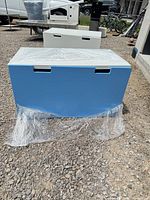 Front view of first blue and white toy chest with matching unit behind