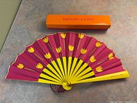 Fan fully opened beside branded box