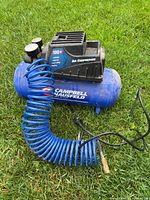 Full view of compressor with coiled hose on grass