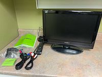 Front view of Insignia 19-inch TV on stand with accessories laid out