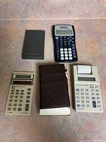 Group shot of all calculators, folio, slide cover and printing calculator with paper roll