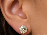 Earring worn on ear showing size, round diamond, six-prong yellow gold setting