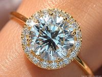 Close-up of ring on finger showing center stone and halo