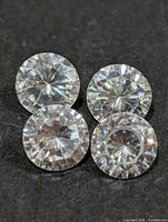Four round brilliant clear stones on dark background