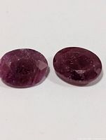 Close-up of two oval rubies showing faceting and inclusions
