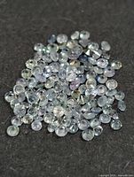 Pile of small round faceted gemstones on dark background