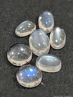Seven moonstone cabochons on dark background