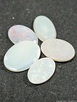 Five oval opal cabochons on dark background