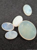 Five opal cabochons on dark background