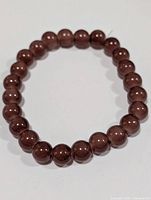 Full view of red rutilated quartz beaded bracelet laid flat